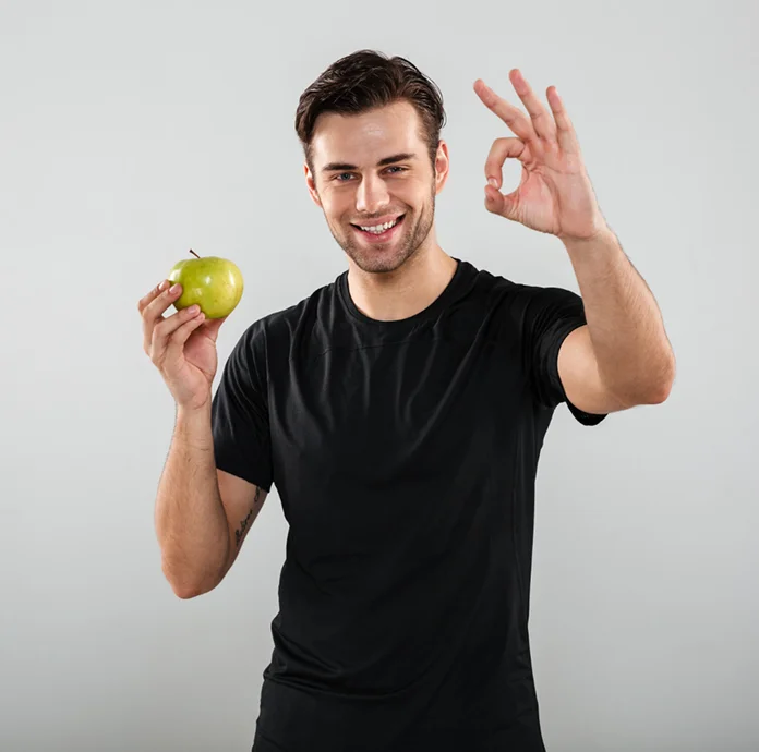 Een glimlachende man met een groene appel, die symbool staat voor gezond eten, een evenwichtige voeding en een actieve levensstijl.